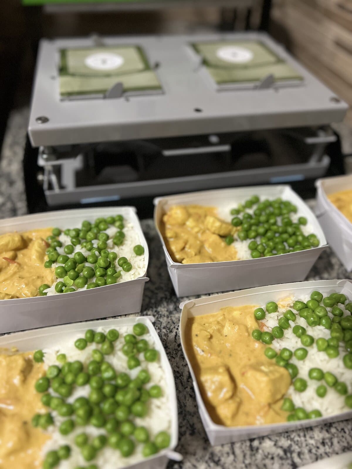 Marmitas de frango com ervilhas alinhadas na seladora durante a produção